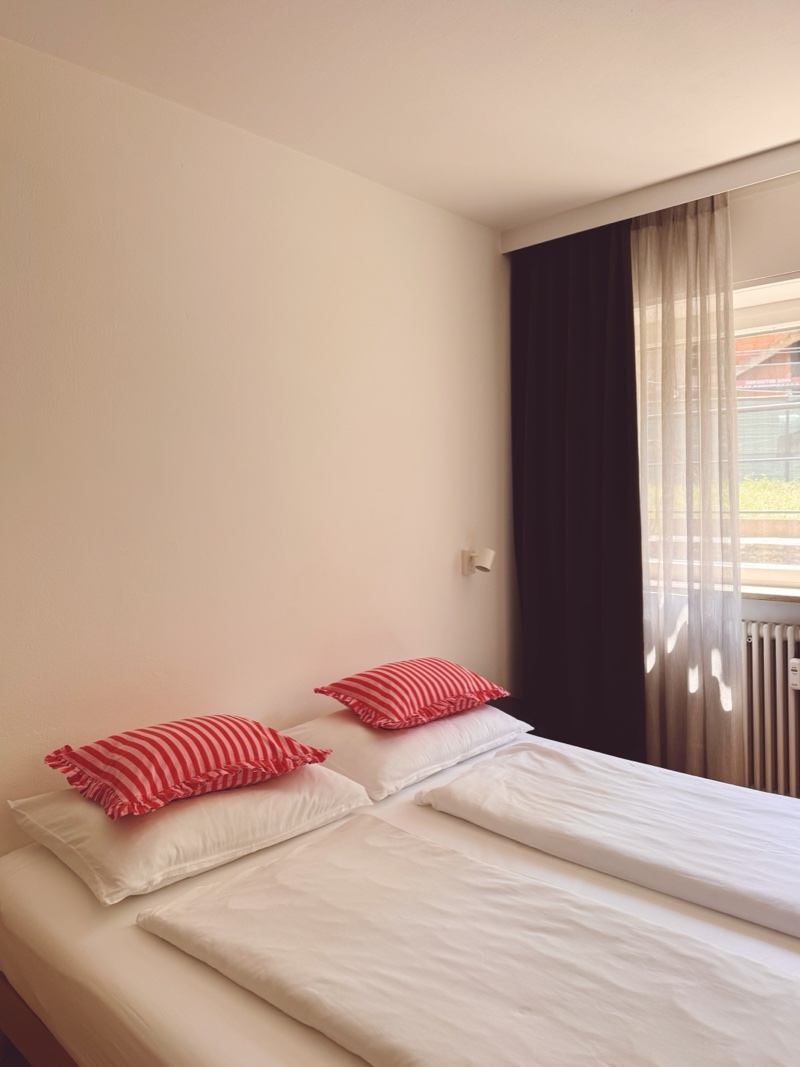 Schlafzimmer 1 – Detail Bio-Bettwäsche mit roten Streifenkissen